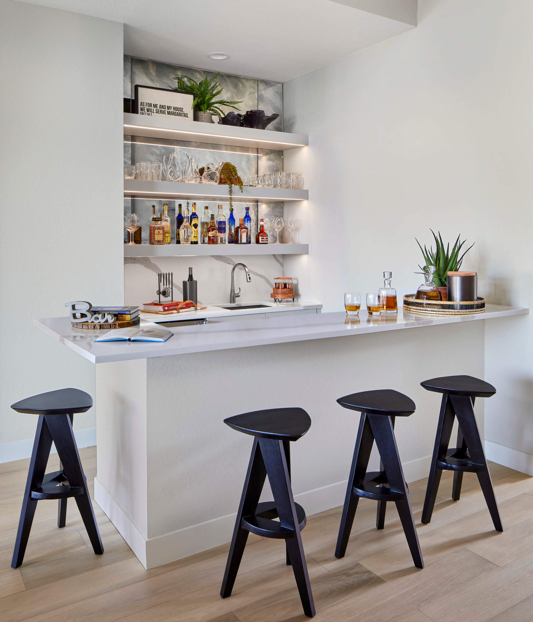 a white kitchen with a bar and stools.