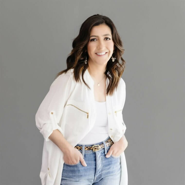 A woman in jeans and a white jacket posing for a photo.