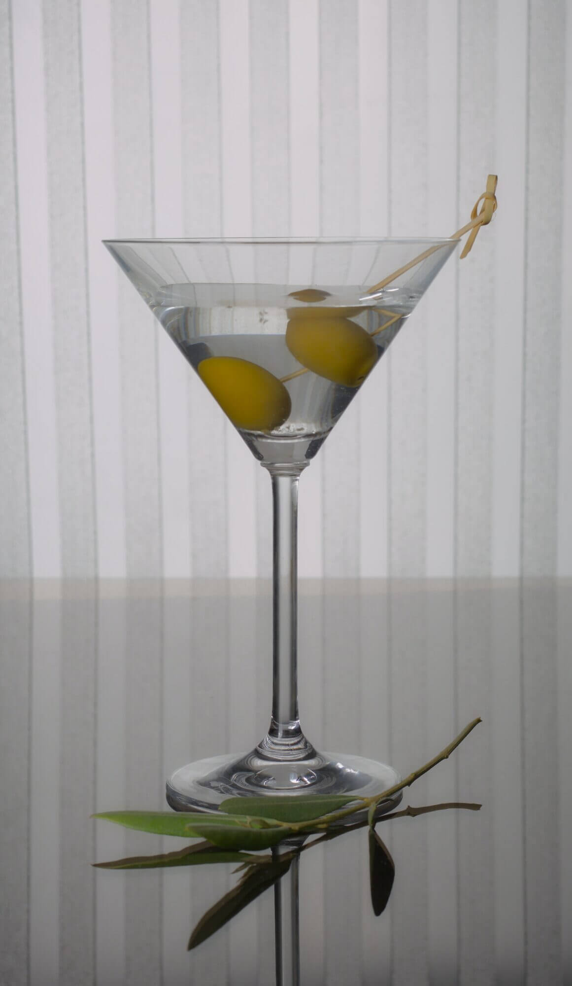 A martini glass with olives in it.