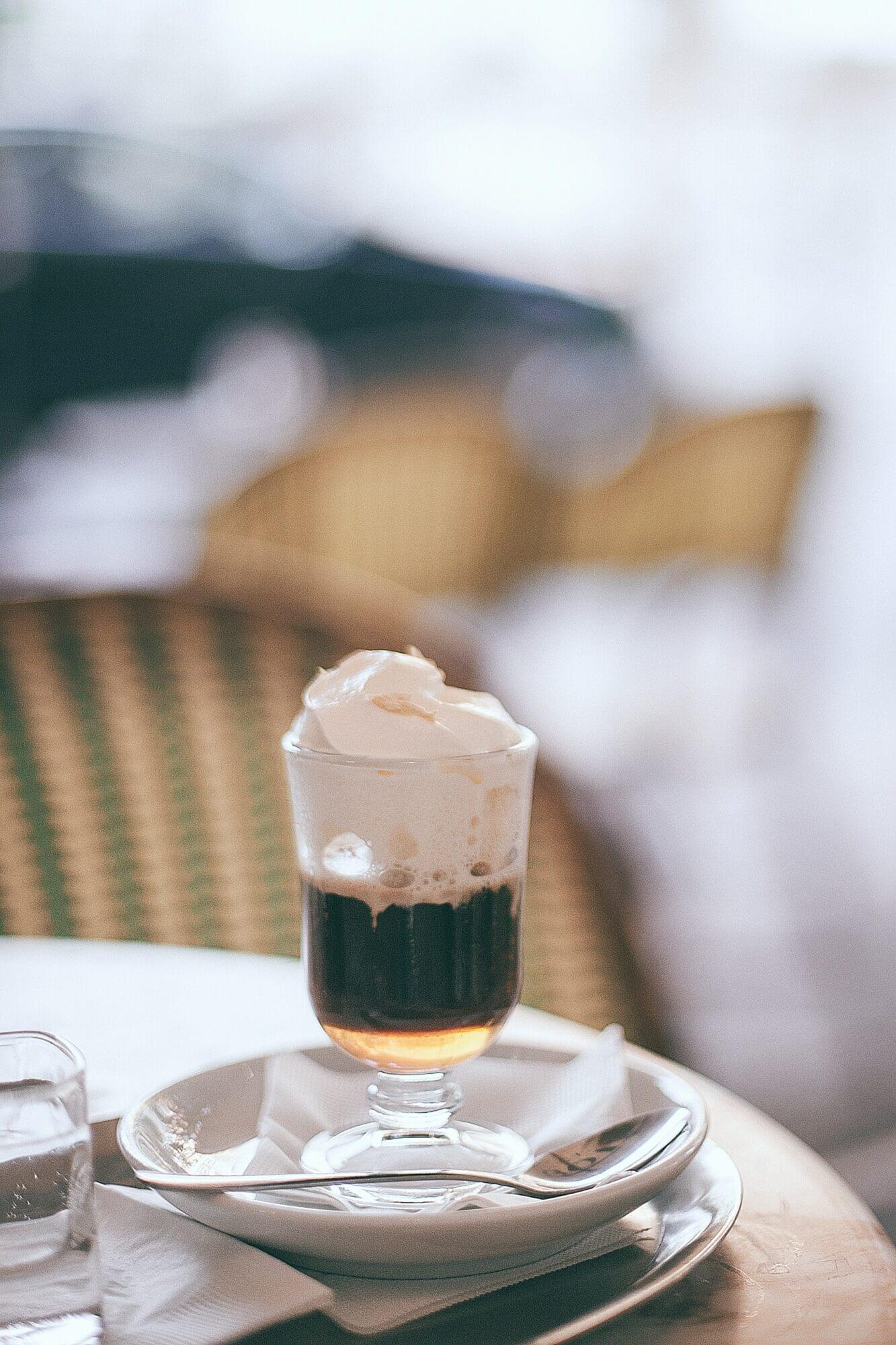 A cup of coffee with whipped cream sitting on a table.