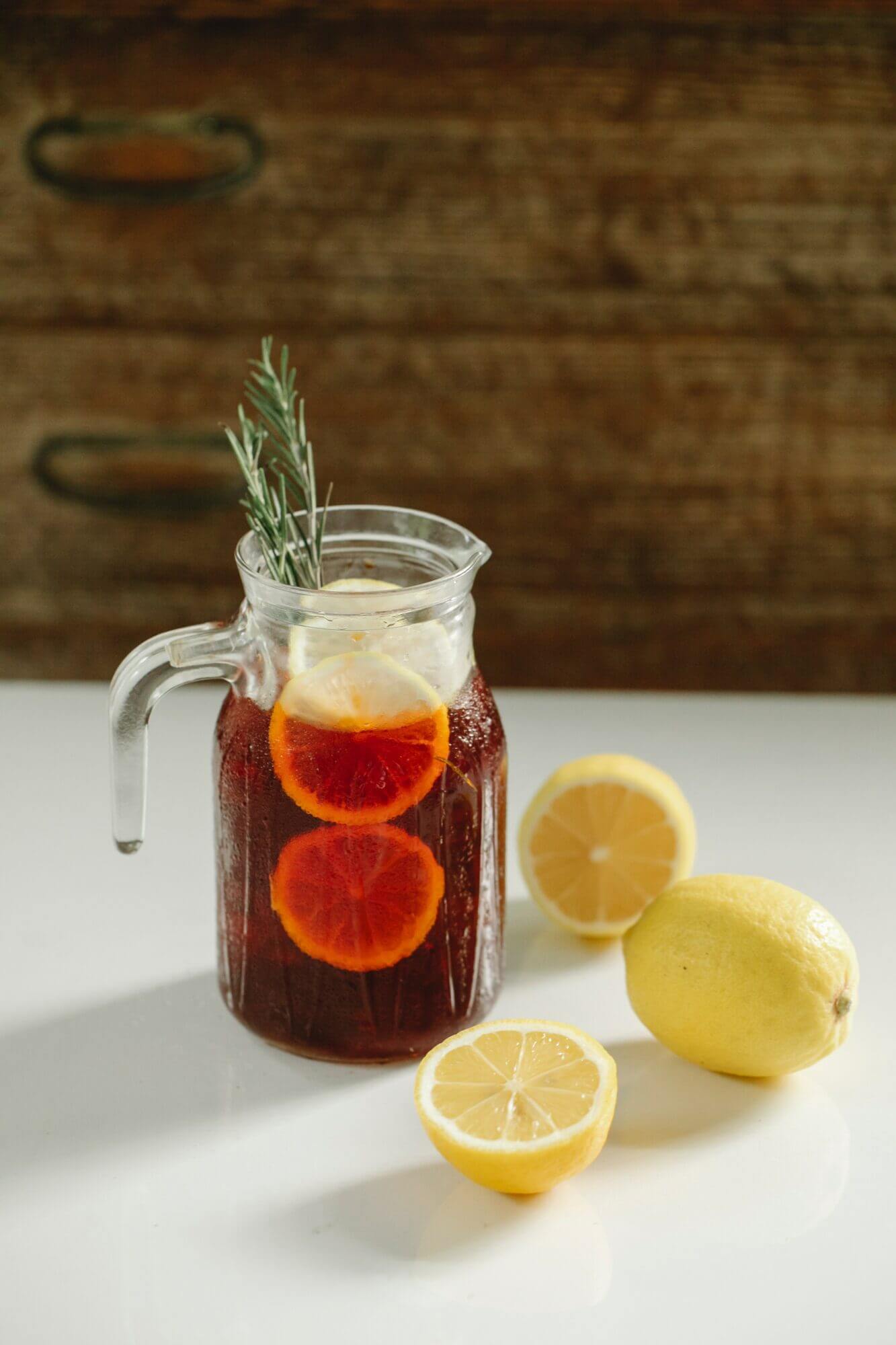 A pitcher of lemonade with lemon slices and sprigs of rosemary.