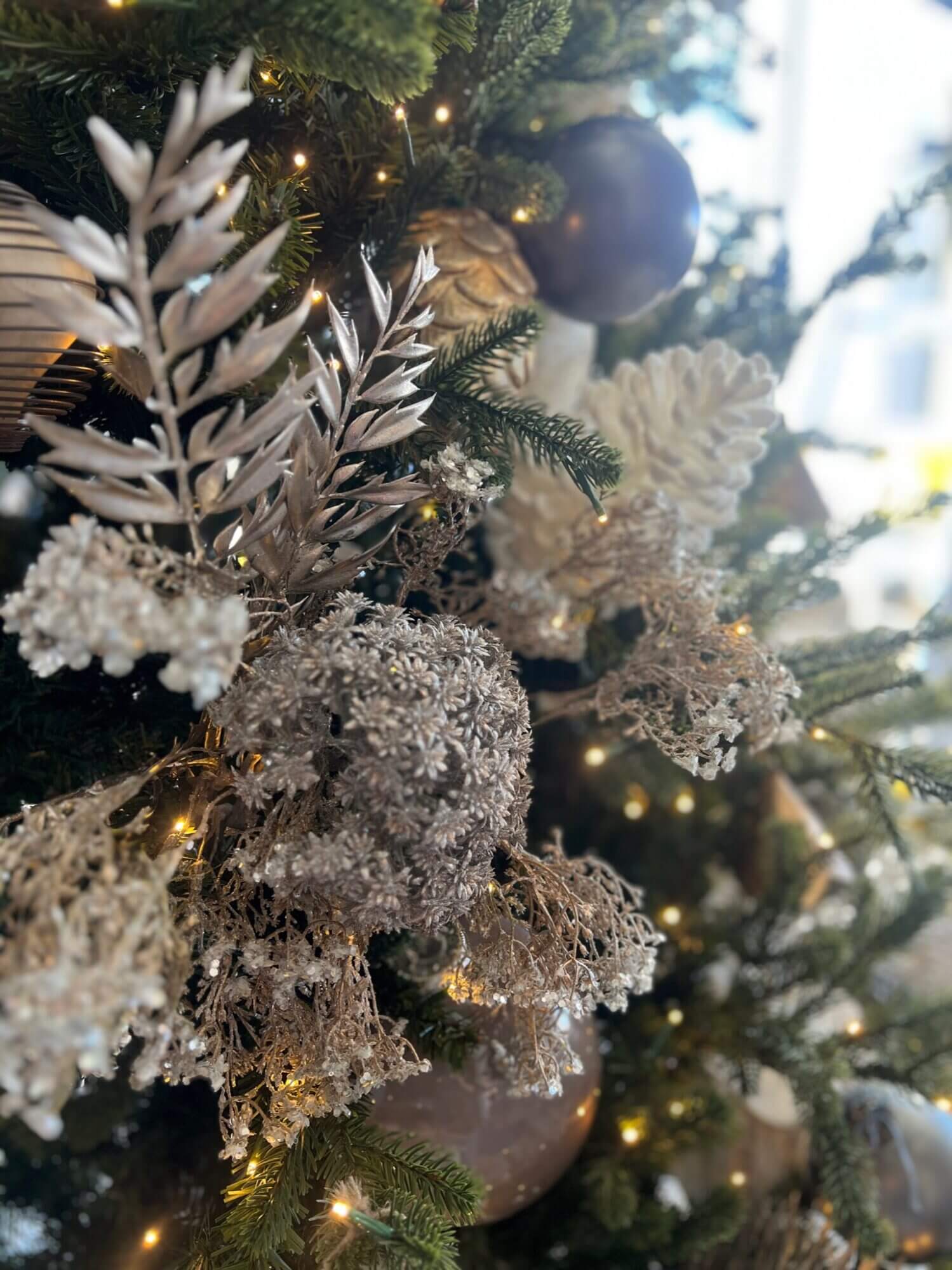 A christmas tree decorated with silver and gold ornaments.