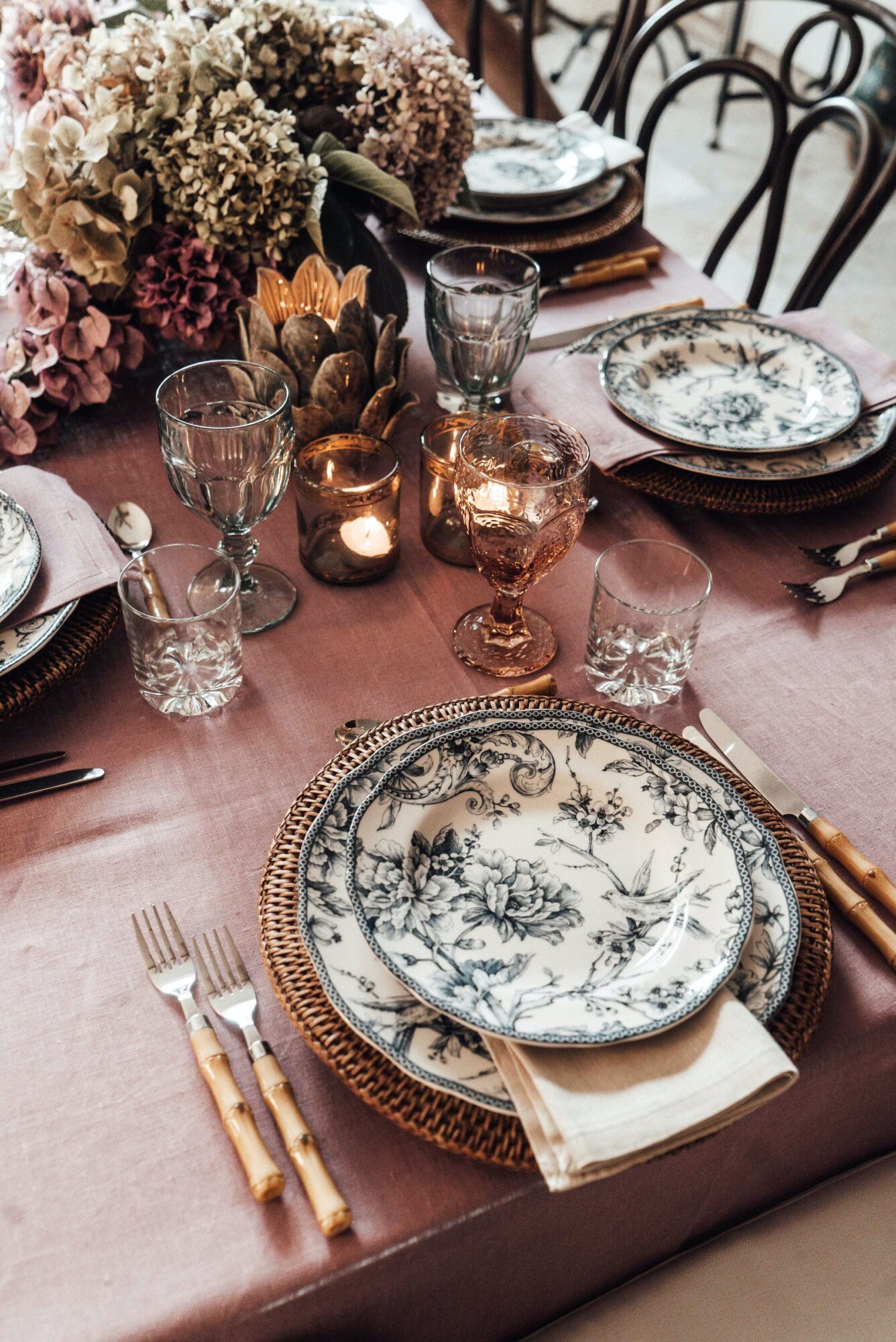 A table setting with plates and silverware on a pink tablecloth.