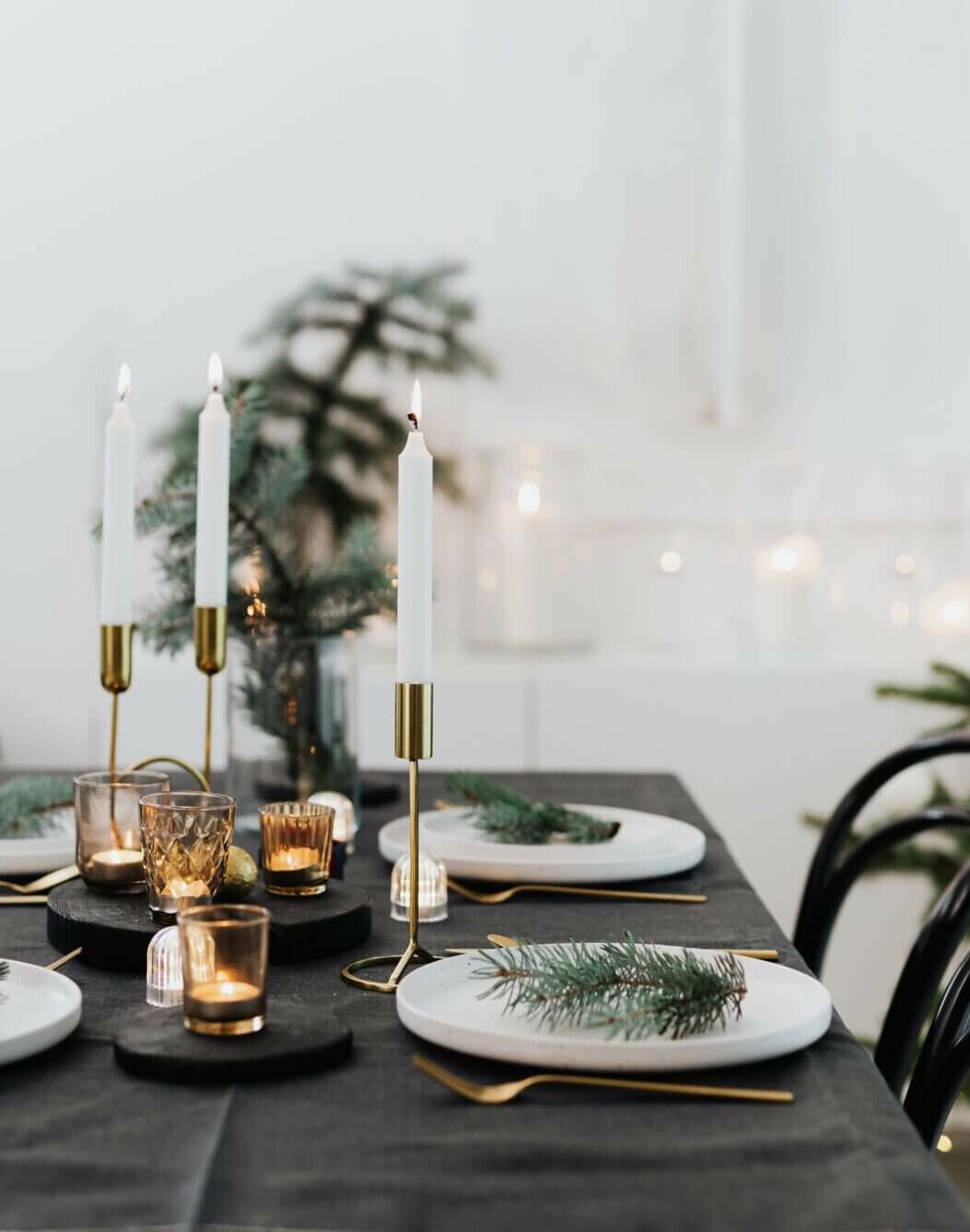 A black and gold christmas table setting in front of a christmas tree.