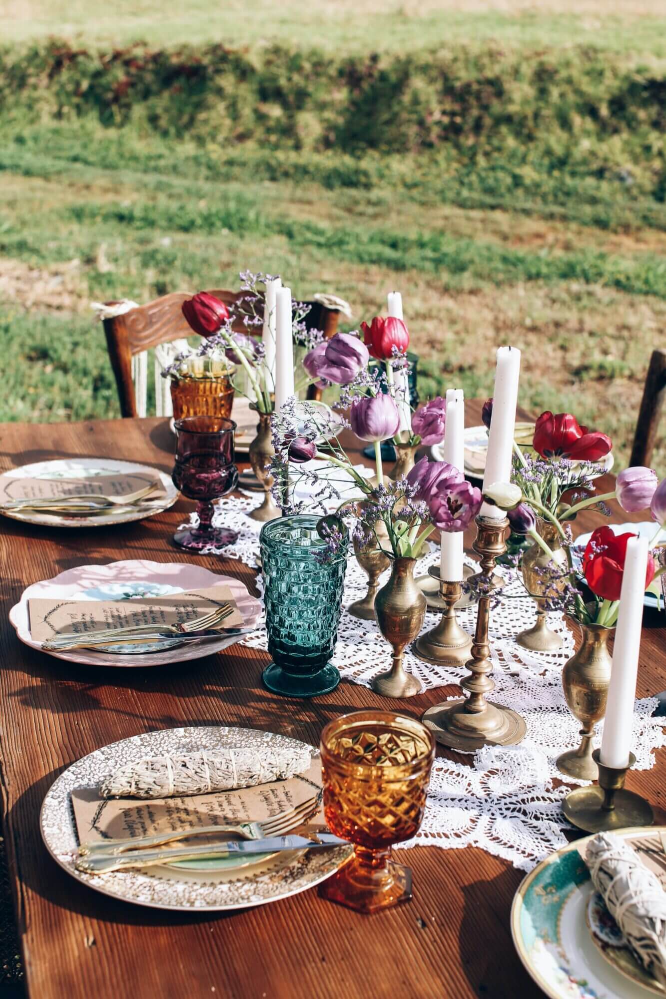 A table set with plates and glasses in a field.