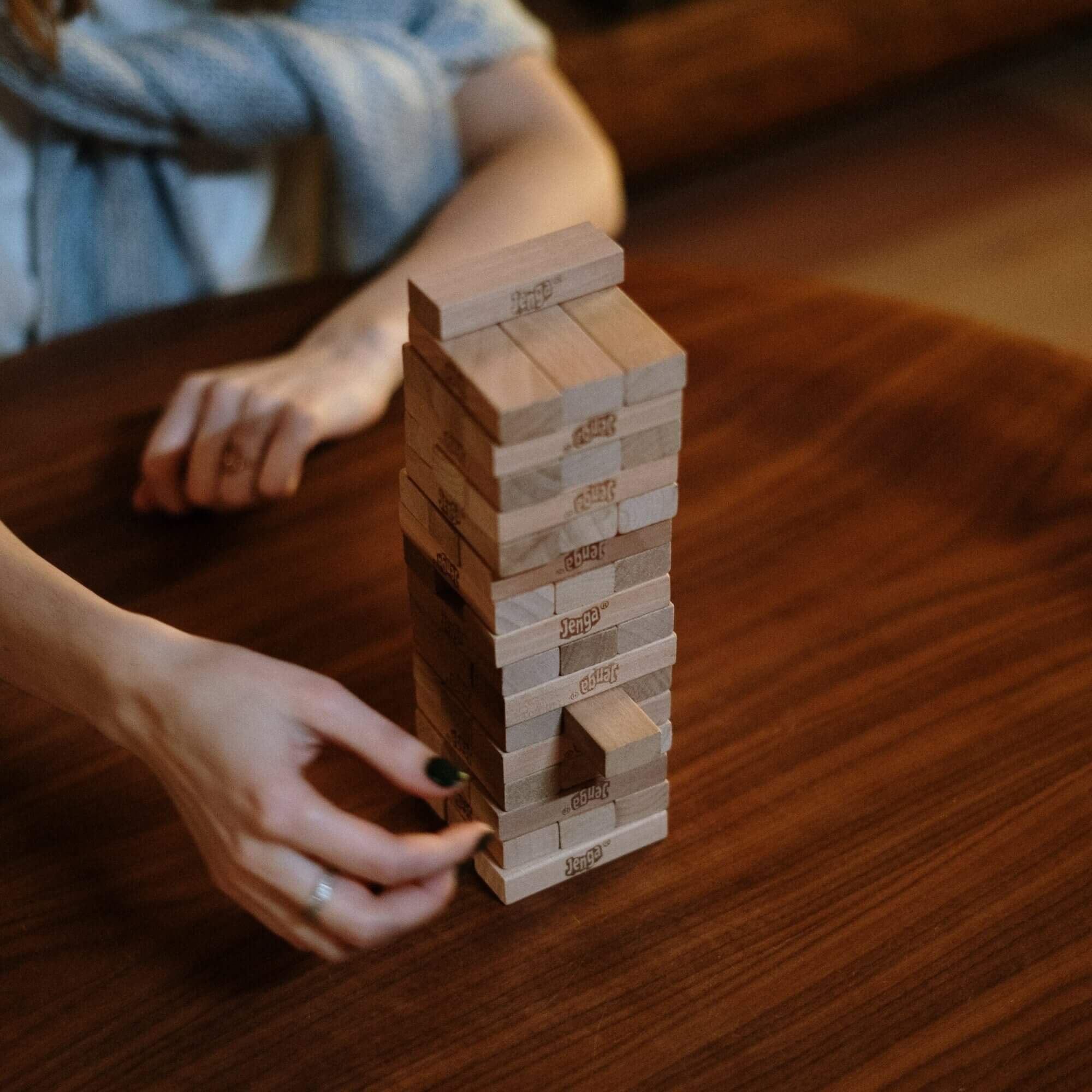 A woman playing a game of jenga on a wooden table.