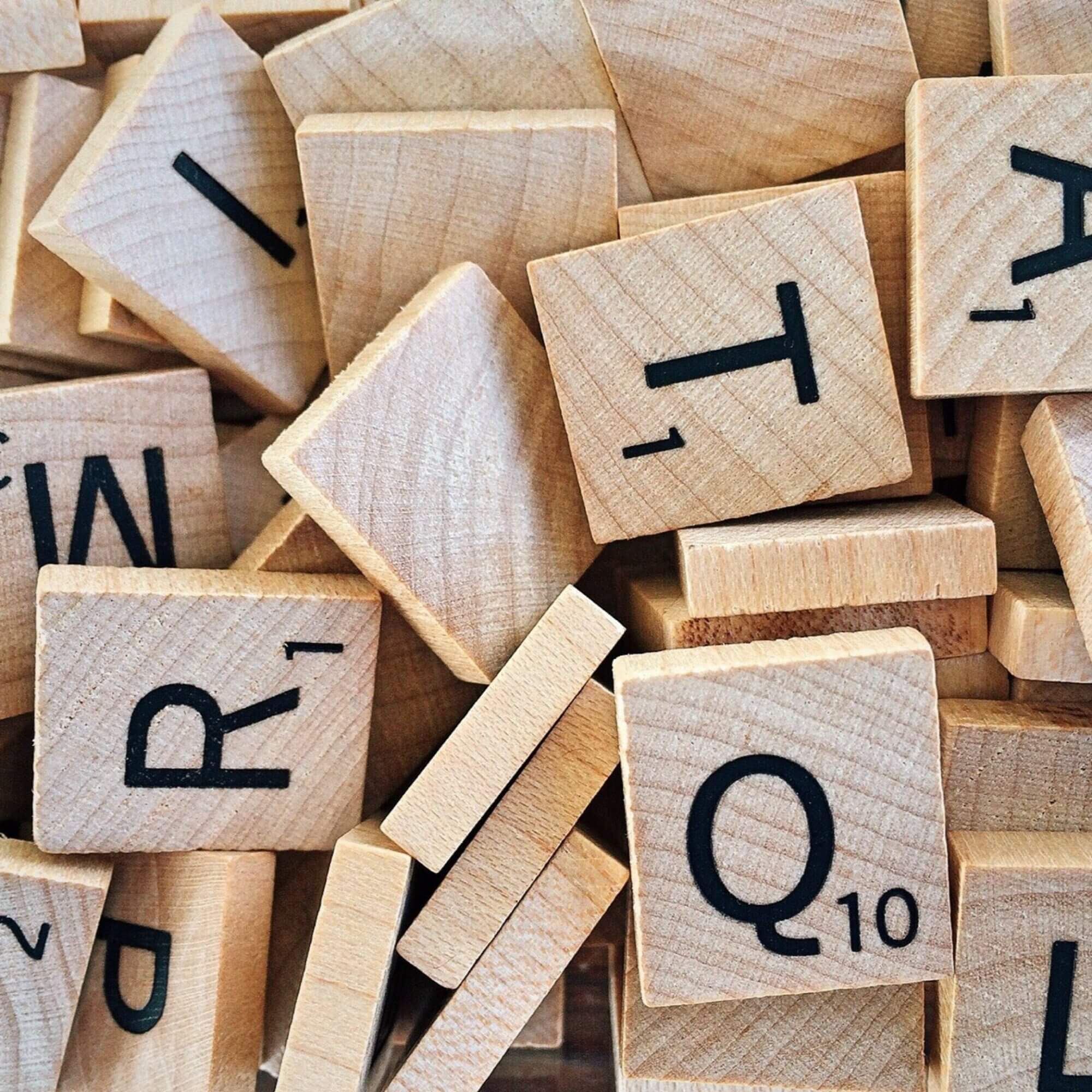 A pile of wooden scrabble letters on a table.